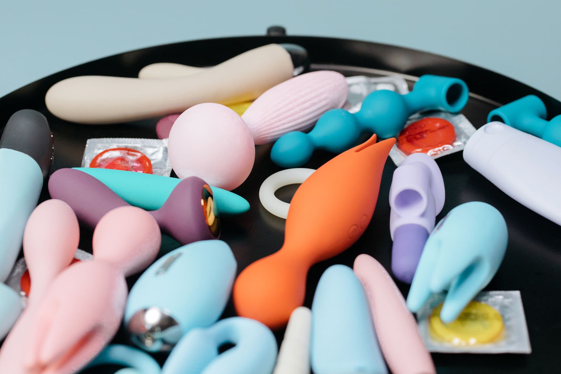 A collection of colorful clitoral vibrators and personal massagers on a black background