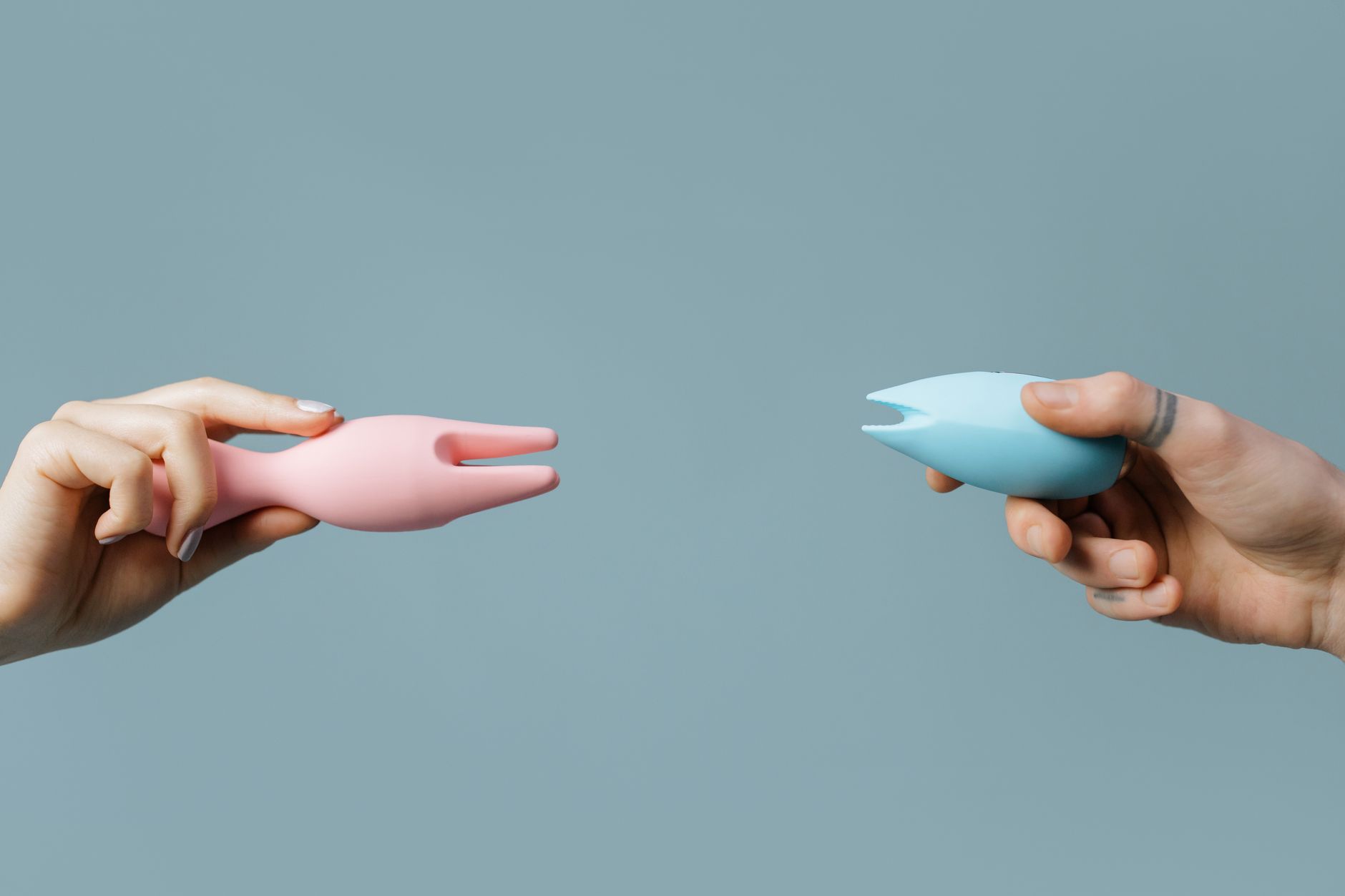 Intimate close-up of hands holding a sleek blue vibrator against a purple background.