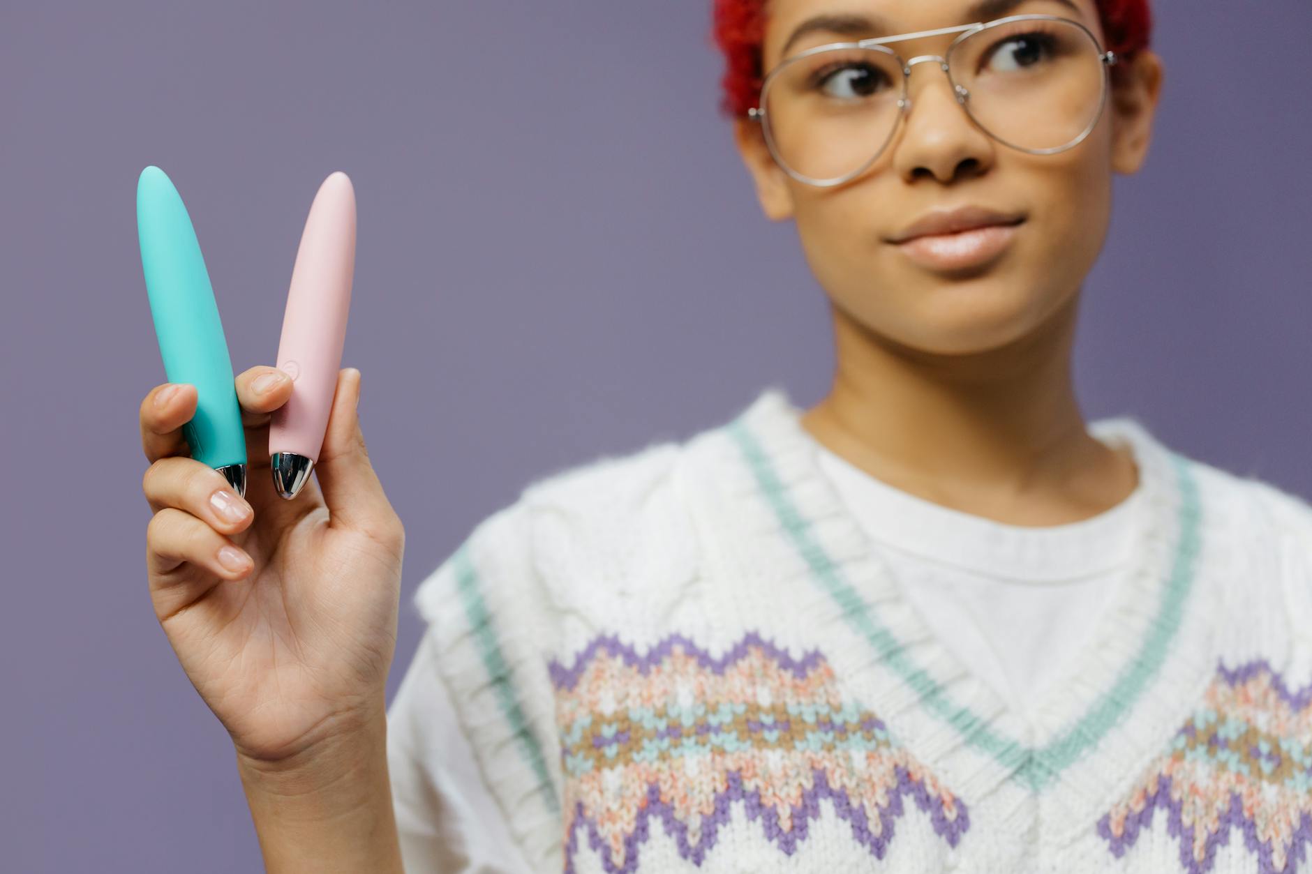 Woman holding colorful lemon clitoral vibrators against a purple background