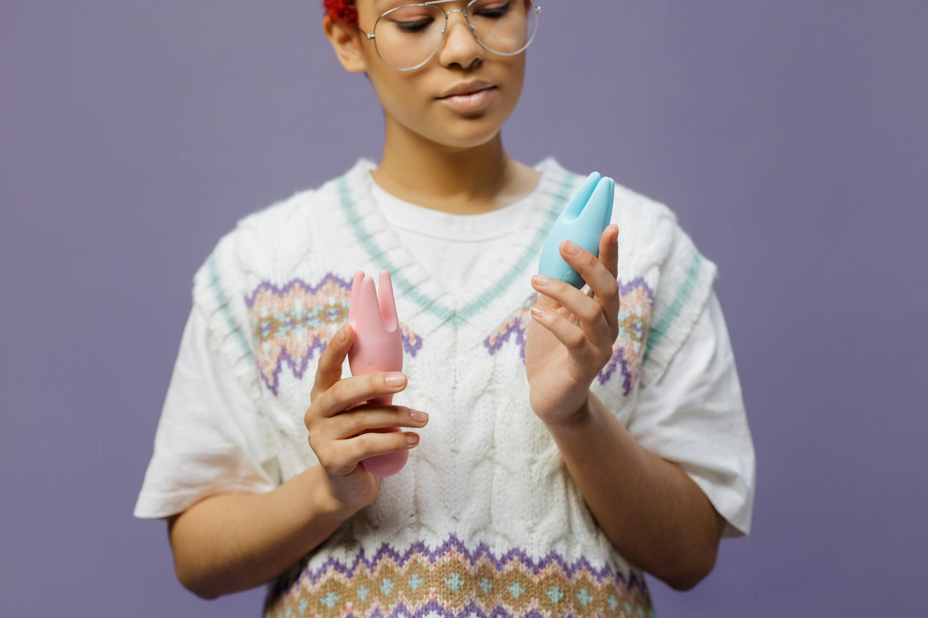 Woman holding silicone vibrators in contemplative pose, considering intimacy options